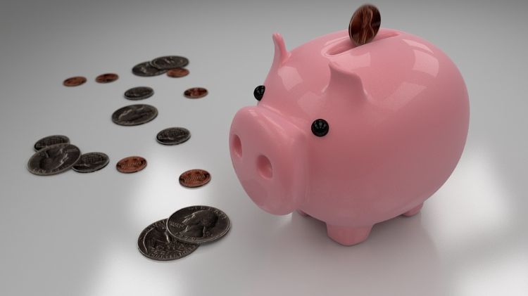 Coins next to a pink piggy bank.
