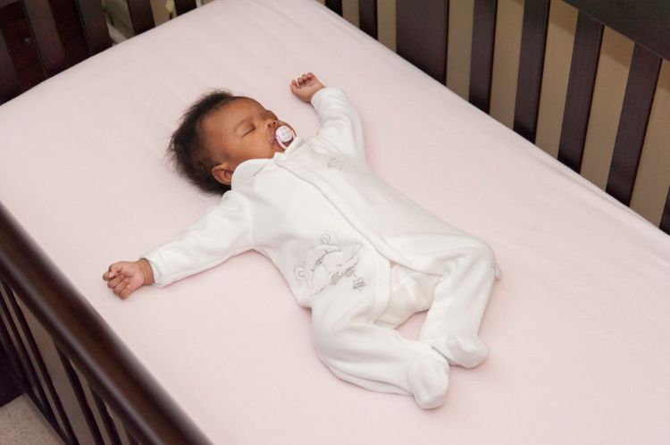 Baby sleeping in a crib on their back without a blanket.