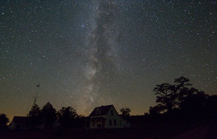 A starry sky over a dark horizon.