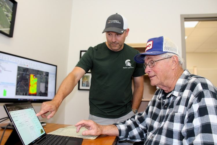 two men look at a computer screen