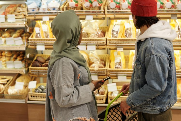 A man and a woman think about what food they want to purchase at a supermarket.